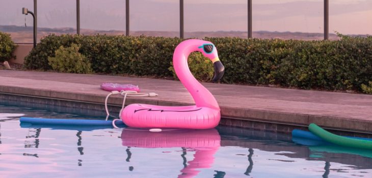 pink flamingo pool floaty floats on the surface of an outdoor pool