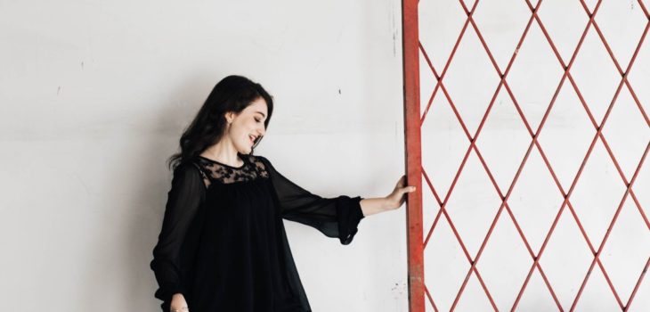 dark haired woman confidently puts her hand on a fence